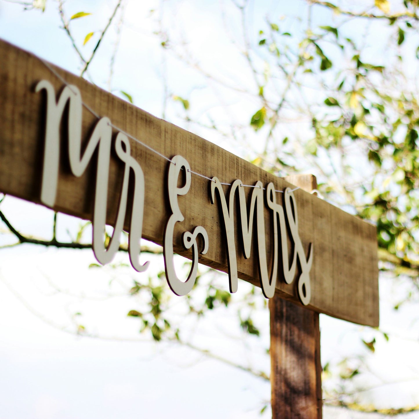 Mr and Mrs wood sign hanging on a wooden post