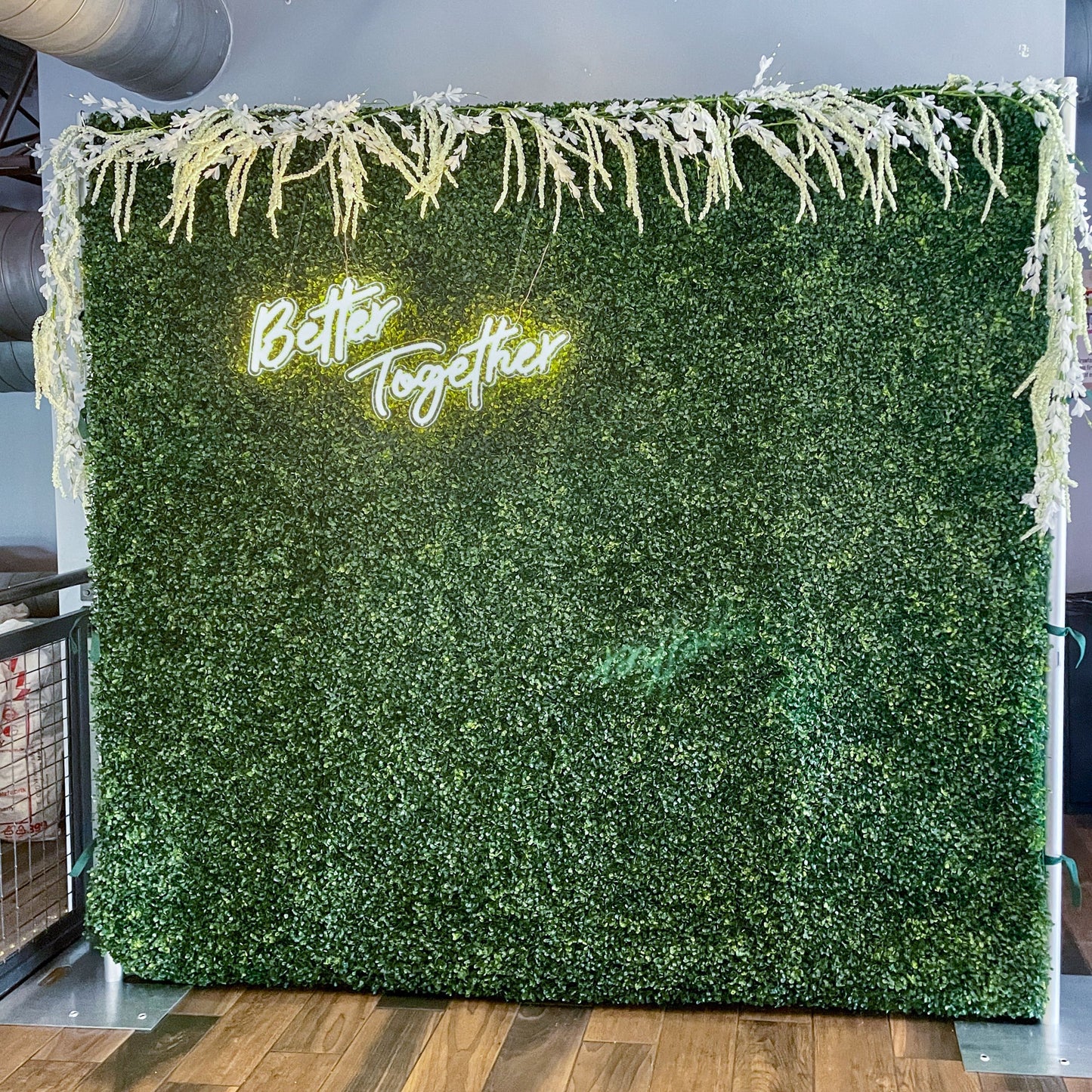 Boxwood greenery wall with better together neon sign and customer supplied garland