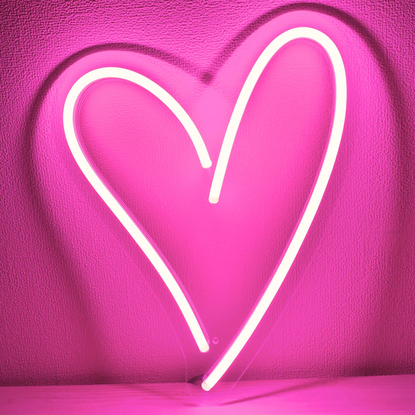 Neon heart sign on a vivid pink background